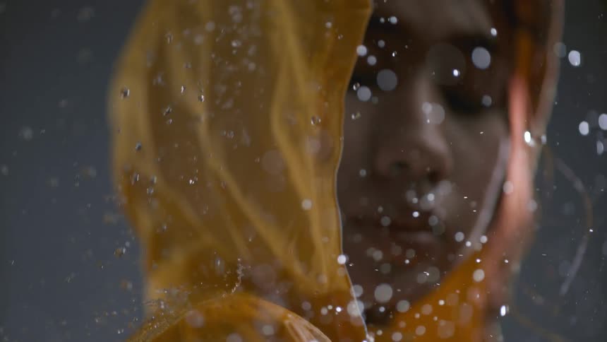 The girl is wearing a yellow raincoat in the rain