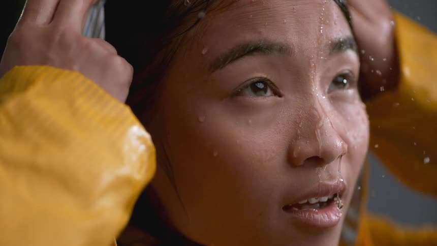 The woman lifts the hood on her raincoat