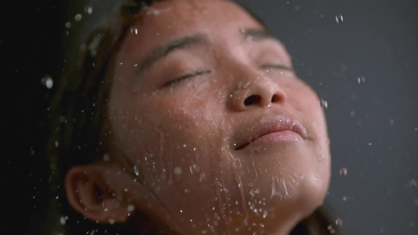 The water is pouring on her face