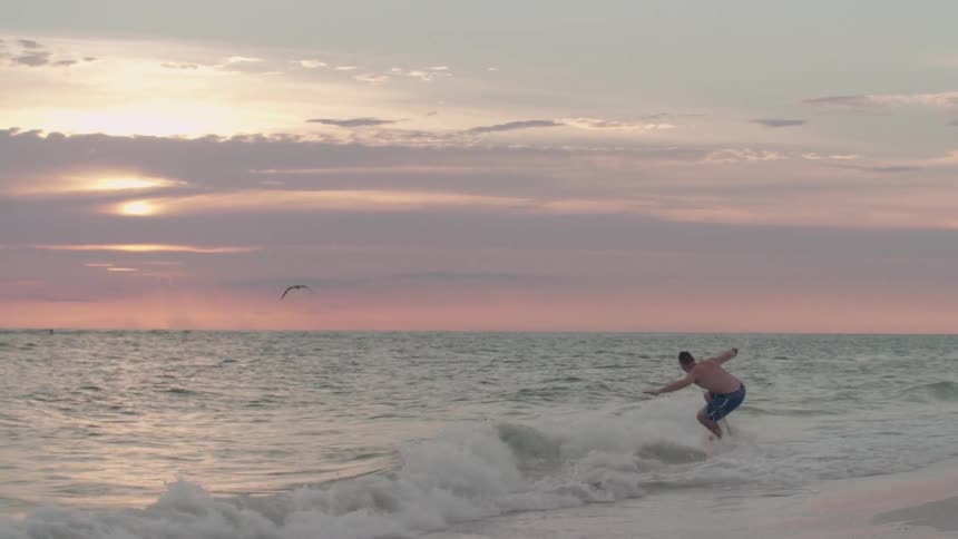A man riding a surfboard at sunset