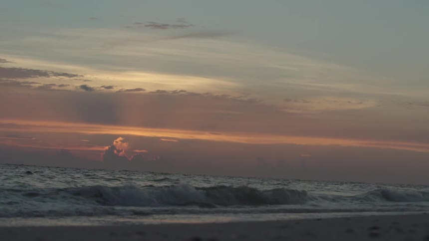 Waves gently crash on the beach at dusk
