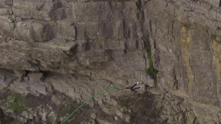 A woman bungee jumps from a cliff