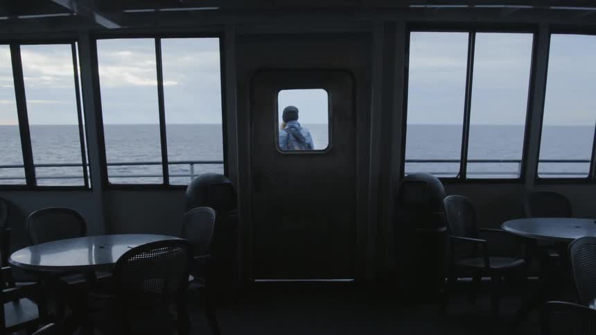 A woman walks through the door from the dining area and steps onto the deck of a ferry