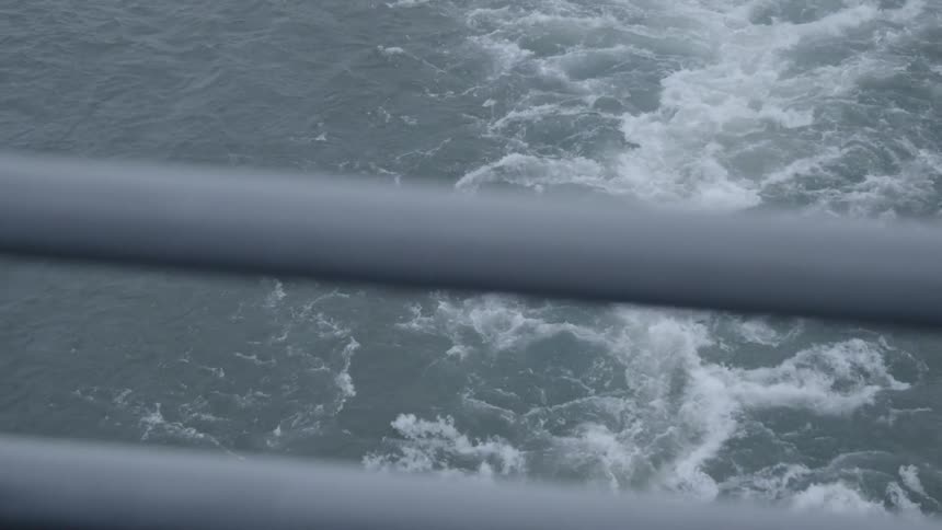 The wake of a ferry seen over the ferry railing