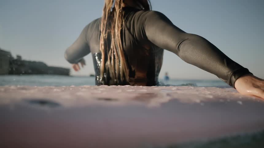 A surfer stands next to a surfboard in ocean water
