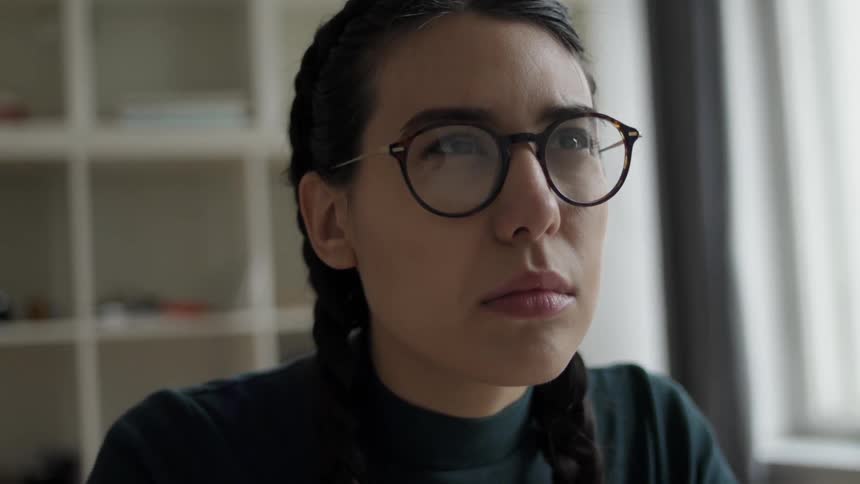 A woman squints and tilts her head as she thinks