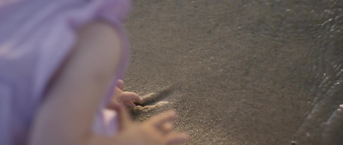 The child is tracing an image in the sand of the shore