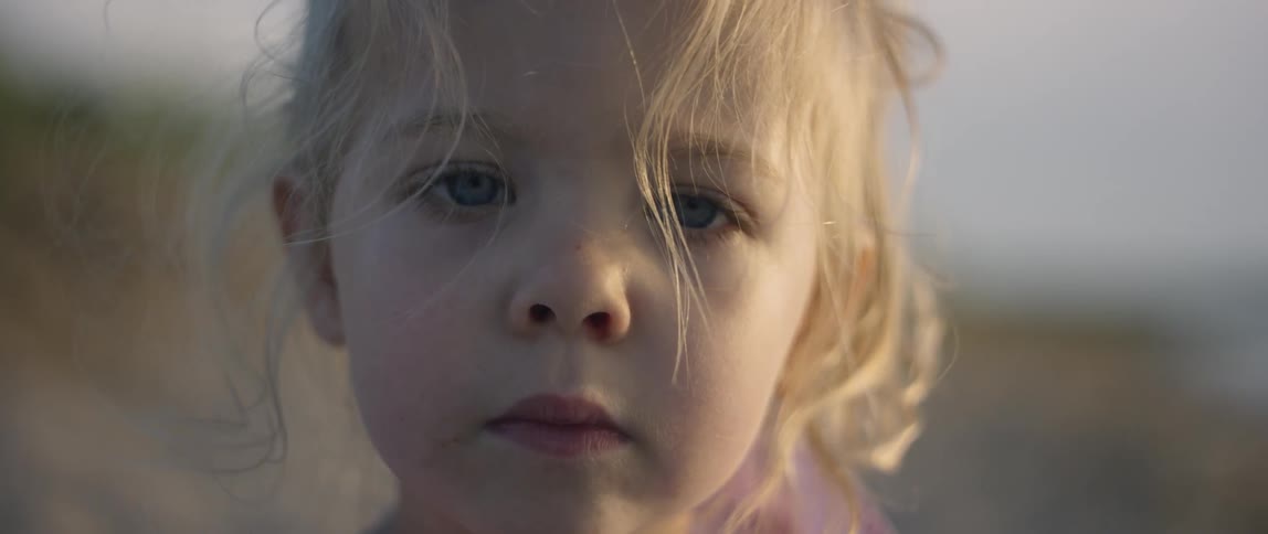 A toddler girl stands outside