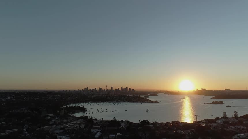 The sun is nearly set by the city on a clear