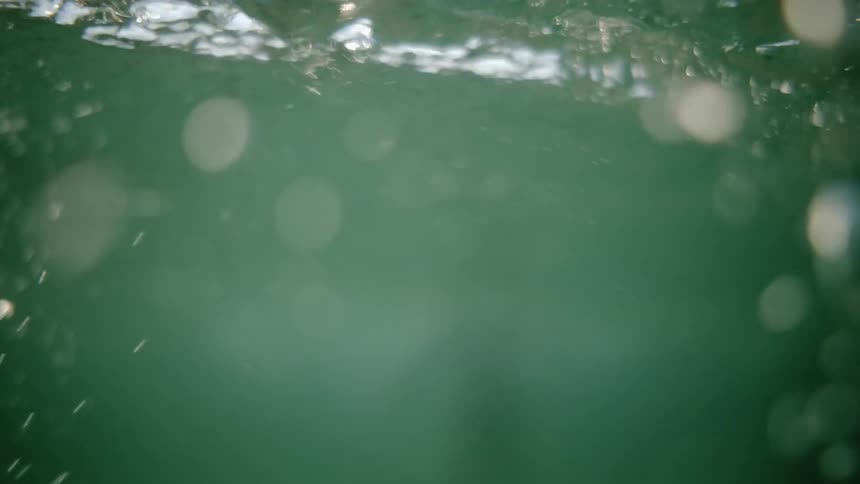 The tide is jostling a person who is treading water in the ocean in daylight