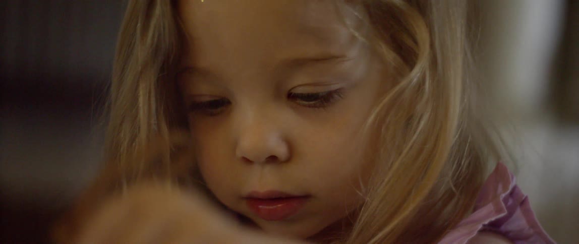 A toddler girl is playing inside a home with her purse during the day