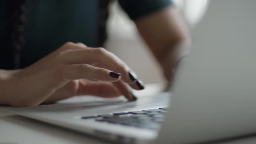 Woman scrolls on the touch pad of her laptop