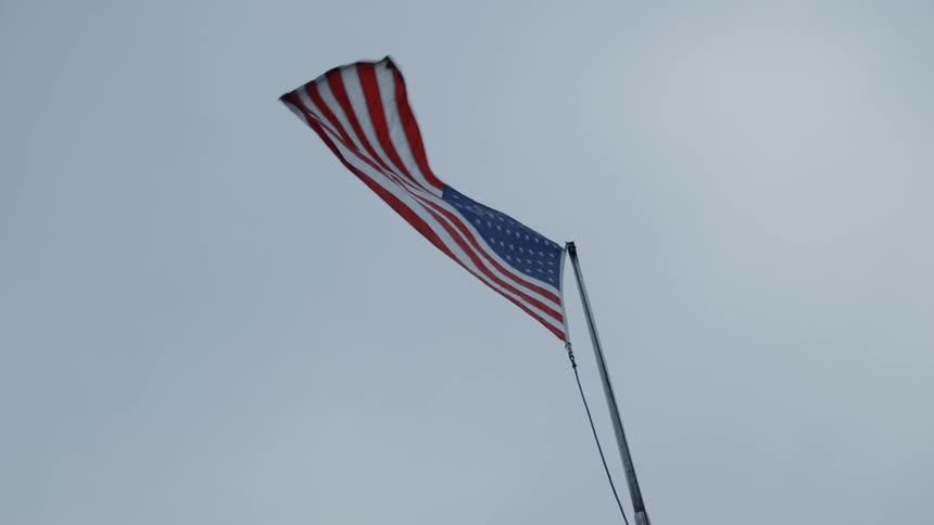 An american flag on a pole blows in the wind