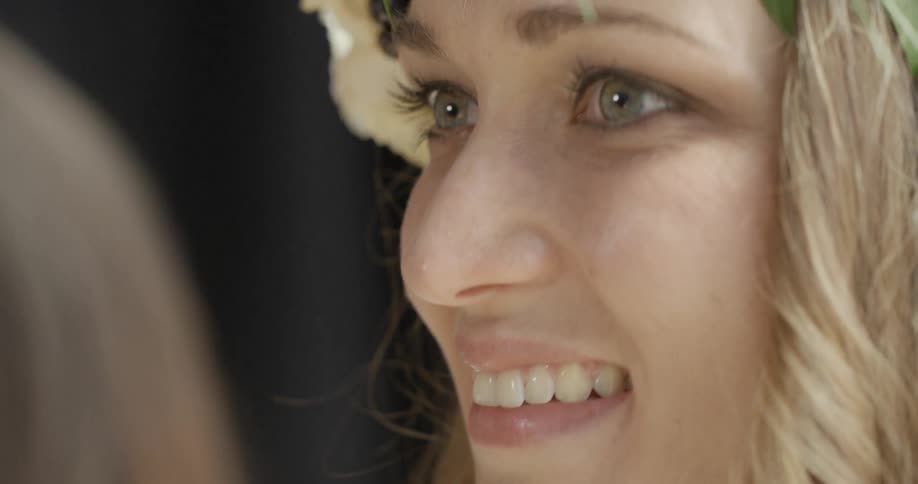 A blonde woman wearing a crown of leaves and berries smiling