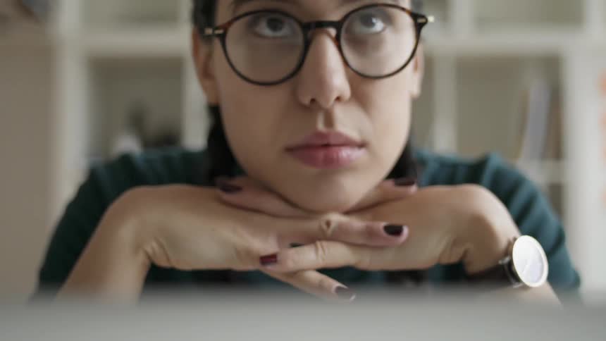A woman leans on her hands at a desk
