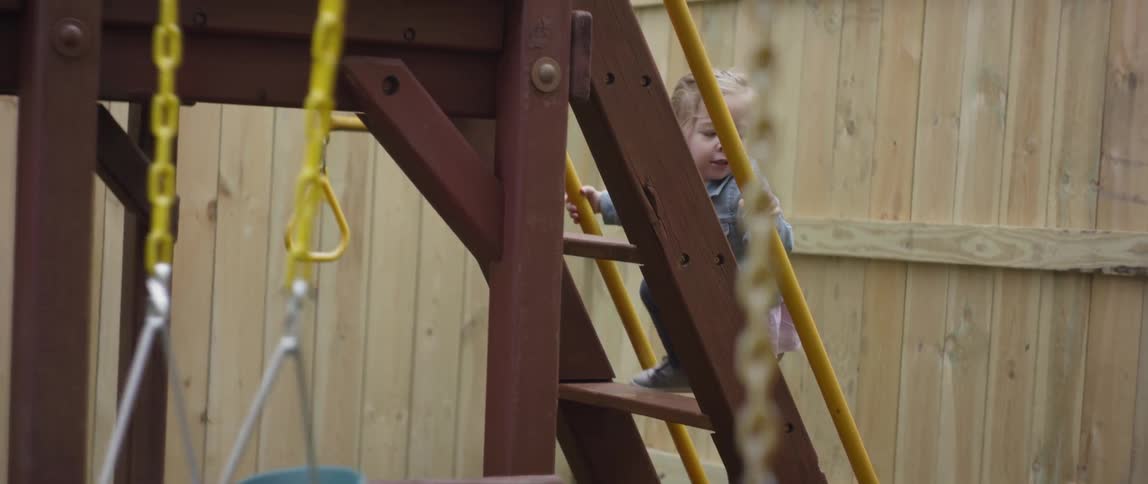 A young child climbs the stairs to a play house