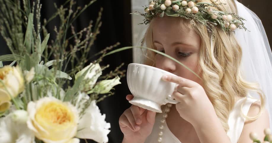 Young girl sipping a drink in a white dress