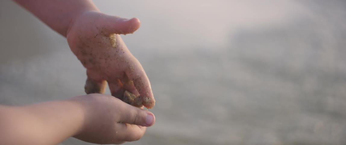 A child plays in sand on a beach
