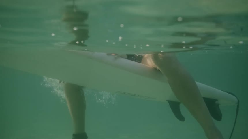 A surfer floats on their surfboard in an ocean