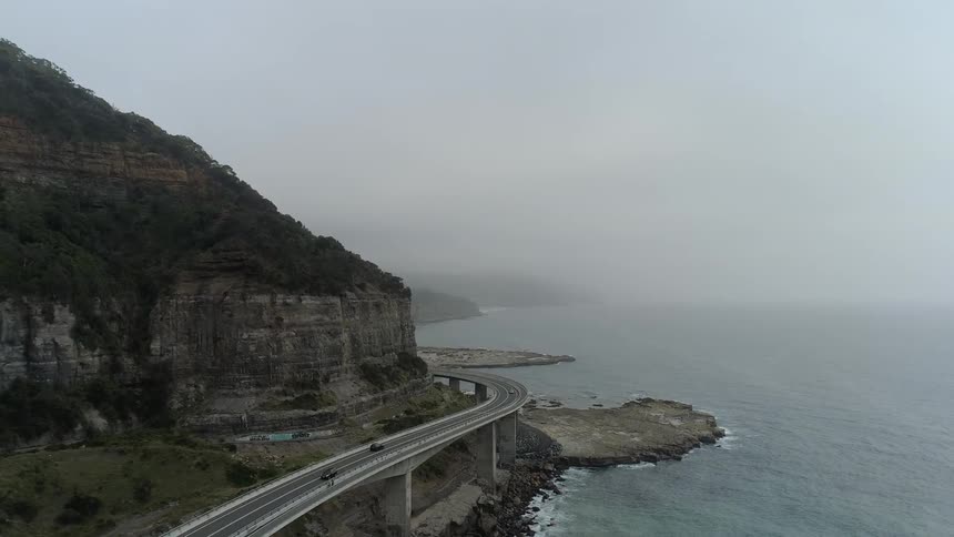 Vehicles travel on a shoreline bridge on an overcast day