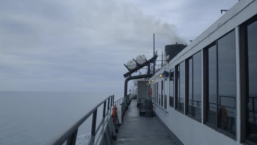 Smoke is billowing from a ship's mast as it sails on the ocean