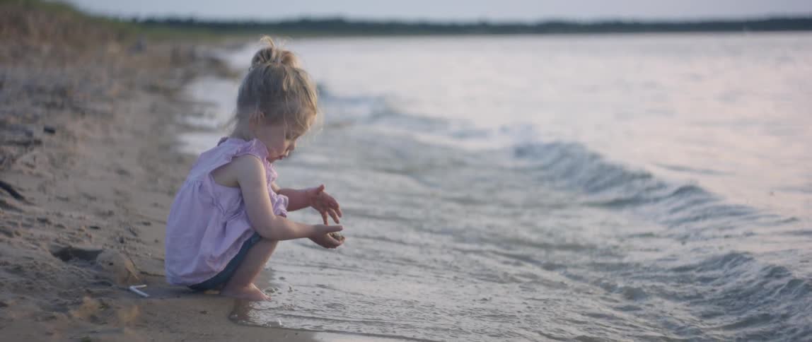 A young child plays in the wet sand