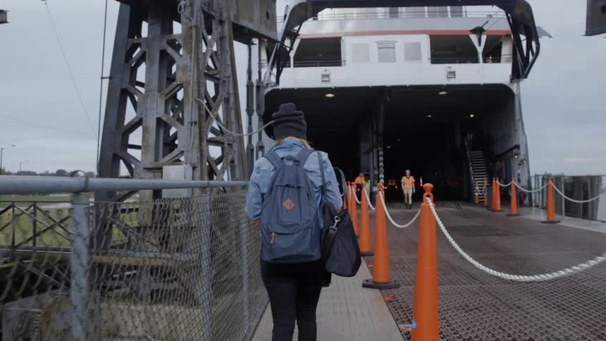 A woman wearing a backpack walks toward the ferry to board