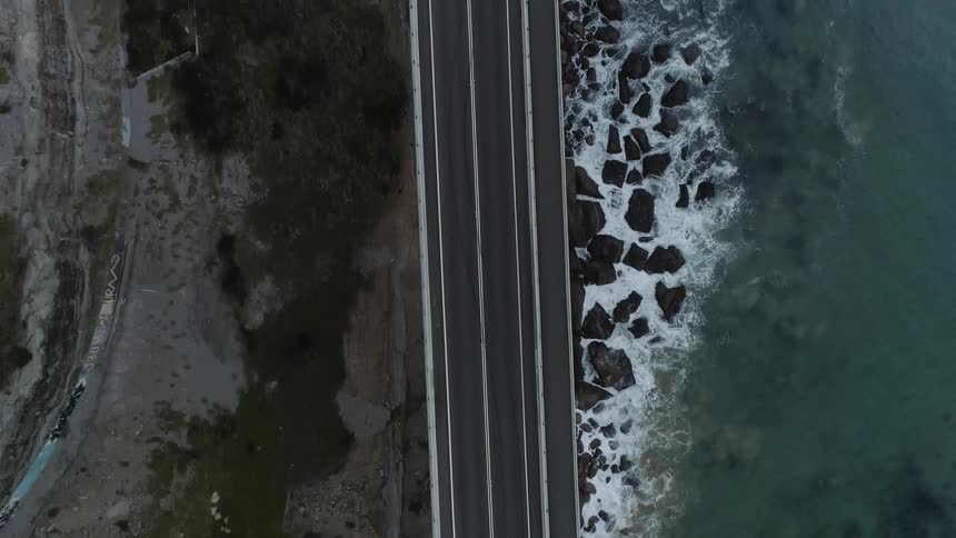 Cars travel on a coastal road