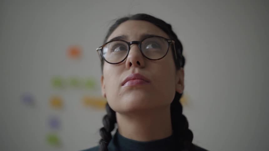 A woman looks around wearing glasses