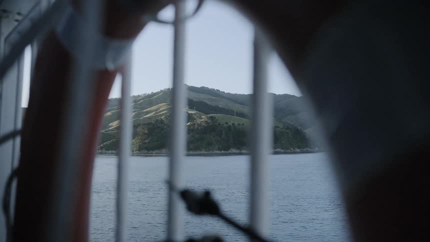 A ship is sailing past a coastline on a sunny day