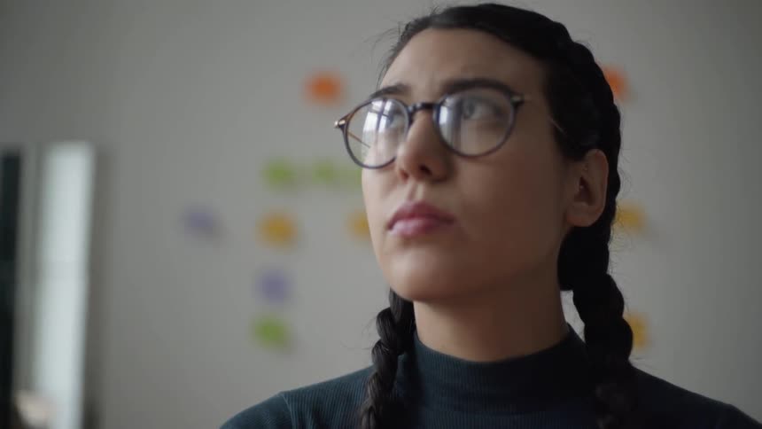 A woman in glasses is deep in thought