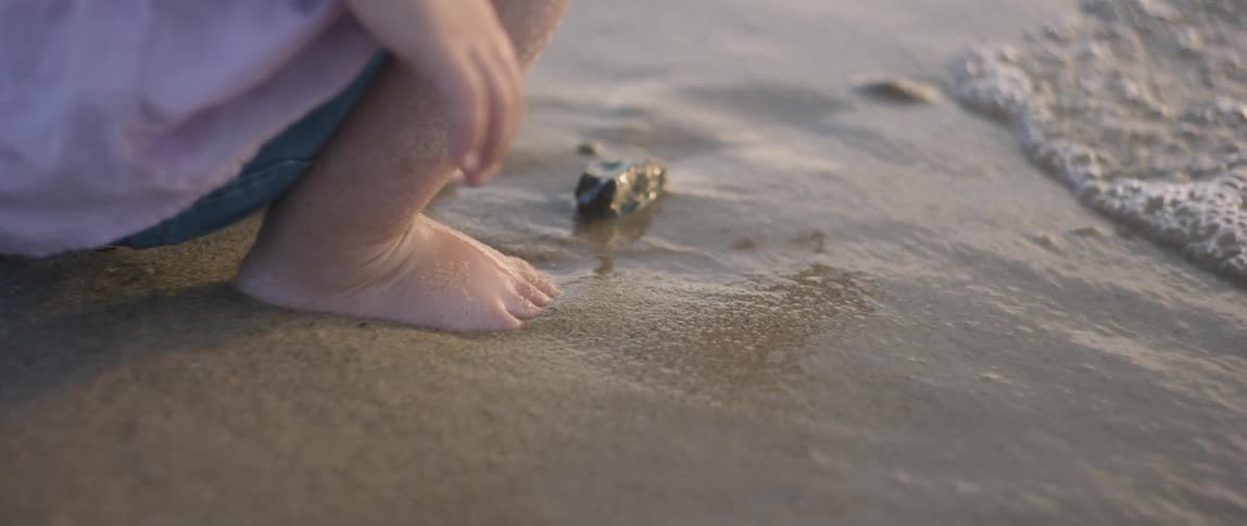 A young girl plays in the sand on the beach