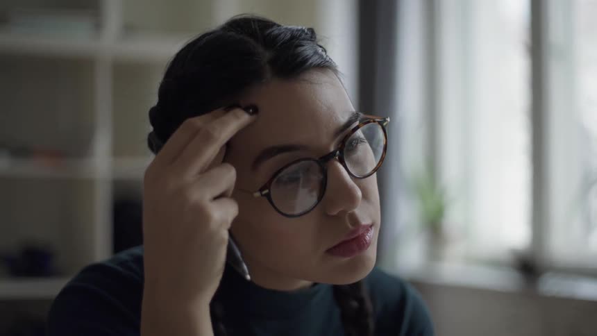 A woman in glasses is deep in thought