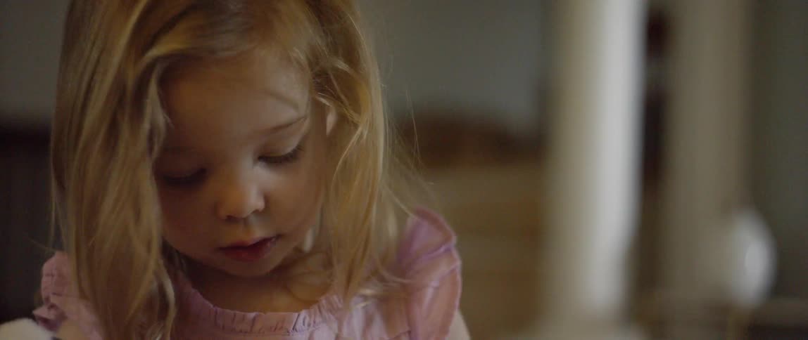 A toddler girl is playing inside a home with her doll during the day