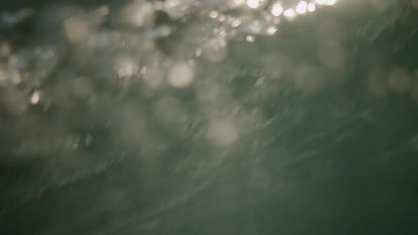 A surfer tries to catch an ocean wave at sunset