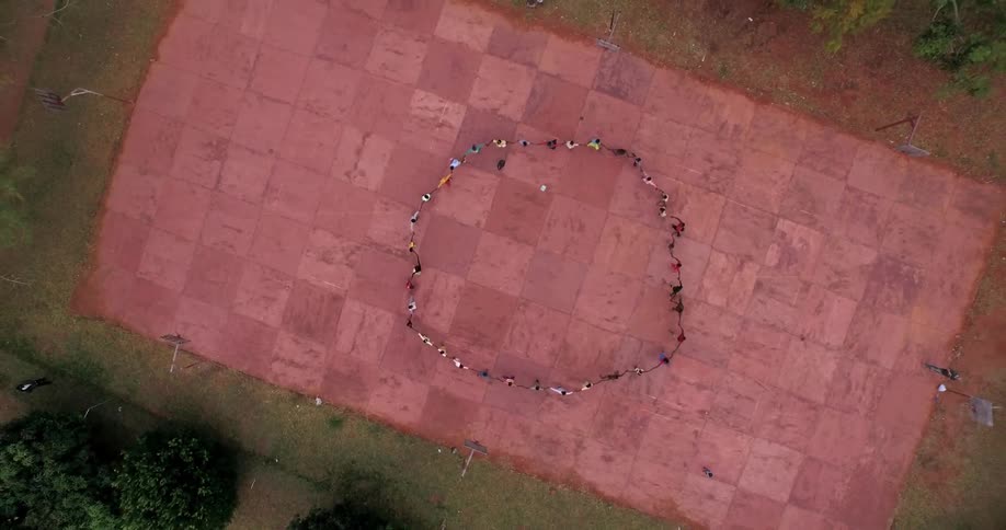 A bird's-eye-view of a circle of people holding hands and running in a circle