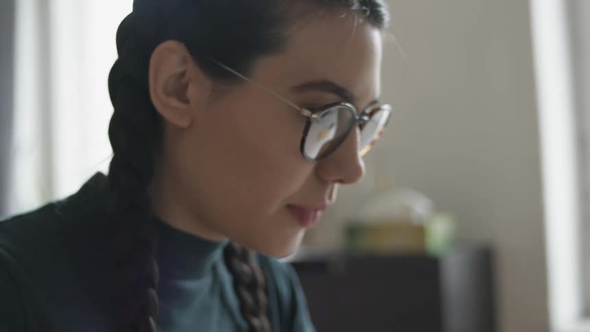 A woman in glasses works on a laptop