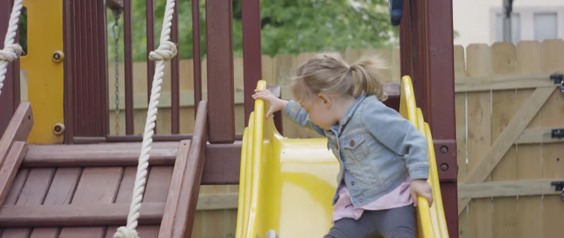 A young girl slides down a playground slide