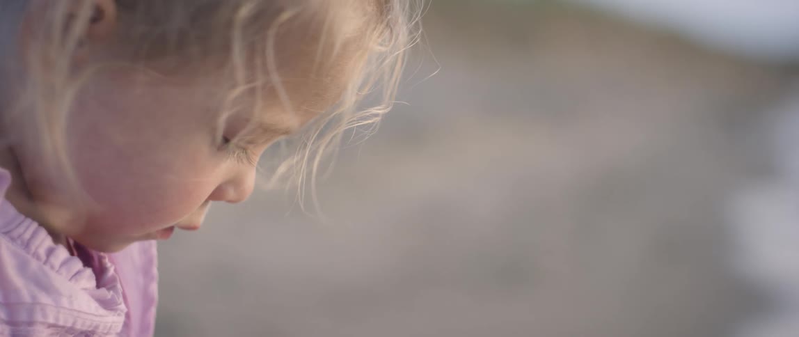 Young girl's hair blows in the breeze as she looks down