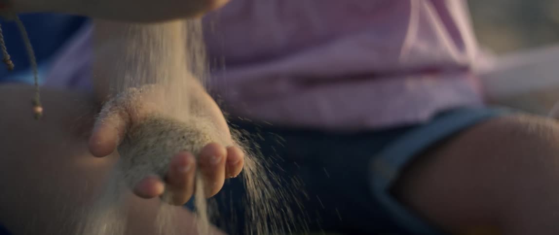 A young girl has sand poured into her hand