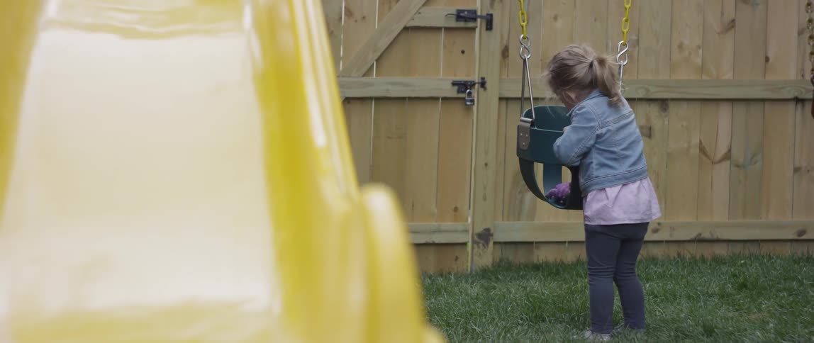 A young girl plays with a doll in a swing