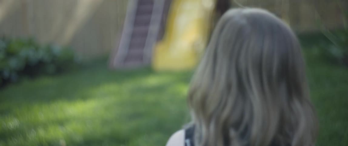 The child walks through the yard as the dog jumps around