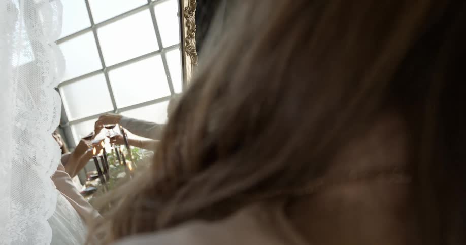 A woman peers through curtains at people celebrating at a table