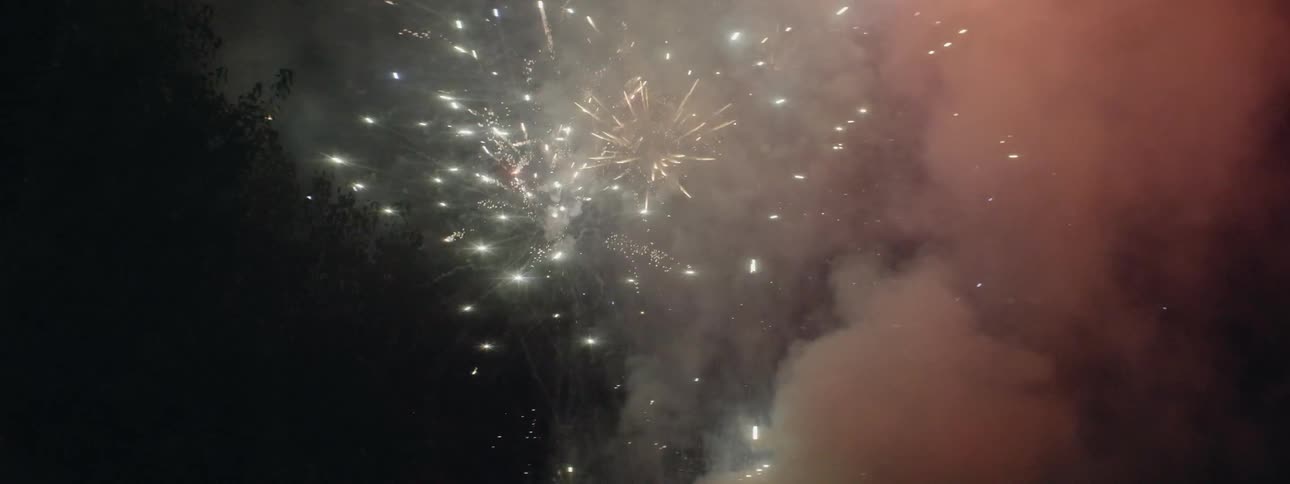 Fireworks explode into a cloud of smoke in the dark sky