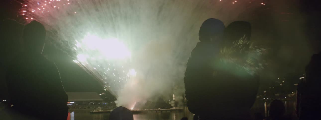 A person holds a child up as the fireworks go off