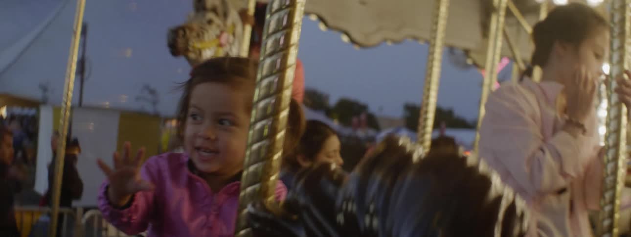 Children ride on a carousel at a carnival at night