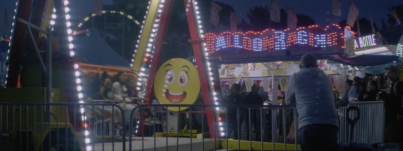 People swing back and forth on a carnival ride at night