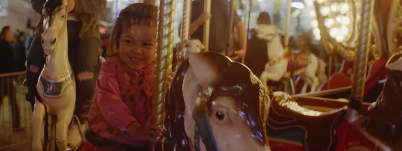The child holds onto the horse on the merry go round