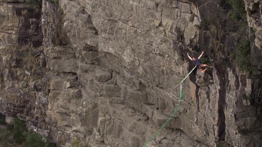 Man leaps from a cliff, hooked to a bungee cord