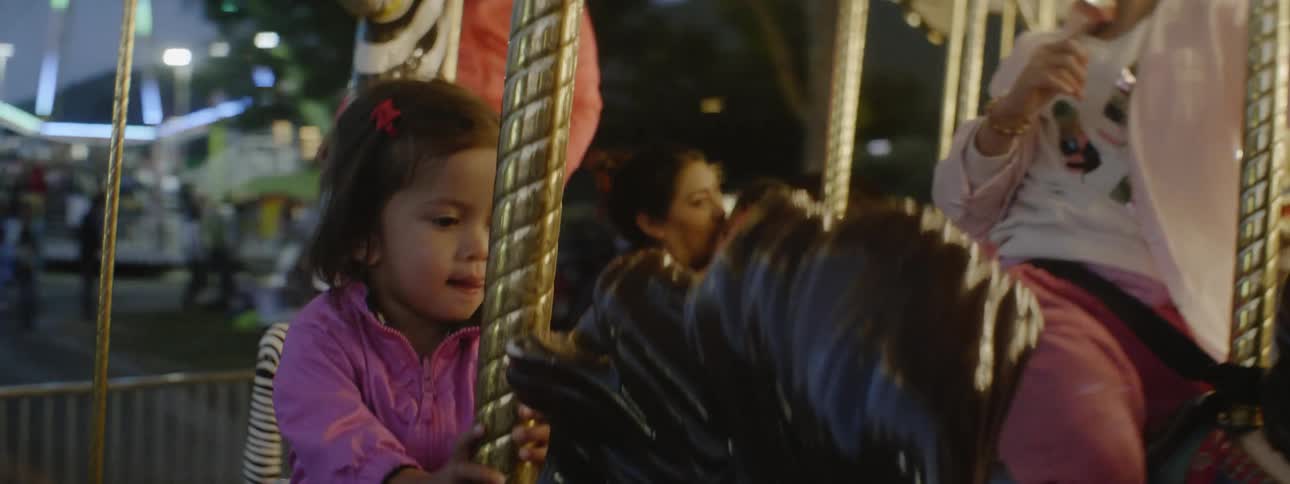 The child has fun riding the merry go round at the busy carnival